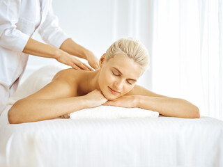 Obraz na płótnie Canvas Beautiful blonde woman enjoying back massage with closed eyes. Spa salon concept
