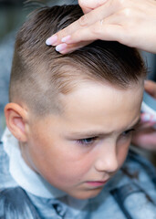 Vertical photo Close up caucasian american pretty school boy trendy haircut at bright modern barbershop.