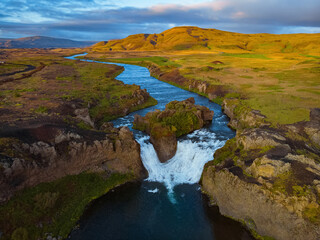Hjalparfoss waterfall in South Iceland at sunset, aerial top view from drone. Beautiful nature landscape