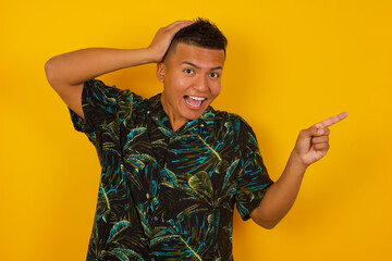 Portrait of young man with shocked facial expression, showing something amazing on blank space, one...