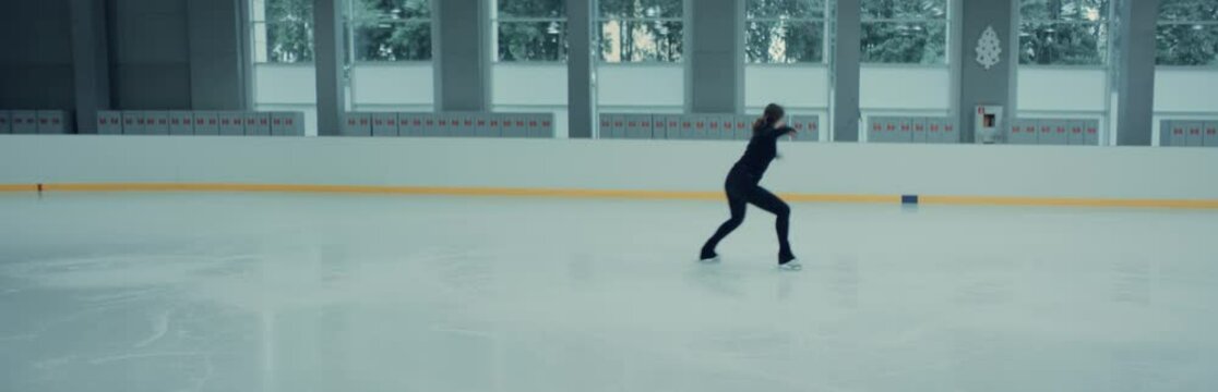 Female ice figure skater falls on ice while practicing jumps on the rink. Shot on RED cinema camera with 2x Anamorphic lens, 75 FPS slow motion