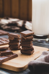 milk dark chocolate tiles on wood cutting board, wooden background