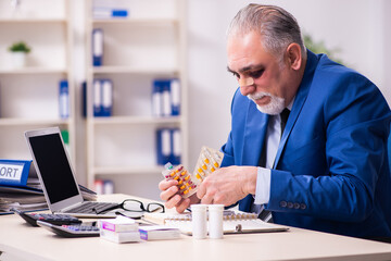 Old face injured employee sitting in the office