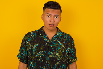 Emotional attractive male with opened mouth expresses great surprisment and frighteness, poses against white concrete background, stares at camera. Unexpected shocking news and human reaction.