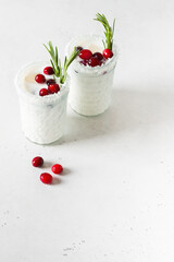 White cocktail with coconut milk, cranberry and rosemary alcoholic or moctail on white background