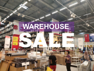 The word WAREHOUSE SALE is clearly written against the background of an image of a department store in a large warehouse. The image has been blurred.