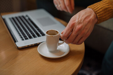 Cropped unrecognizable man drinking espresso on business meeting in cafe.