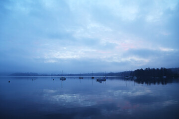 cloudy dawn time near lake. boat and reflections with a glance of red sunset lights up the cloud. 