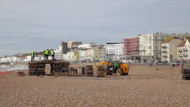 Telehandler builds bonfire from wooden pallets on stony beach in Hastings