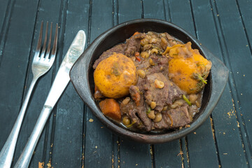 Beef stew in a bowl on a black background, close-up view