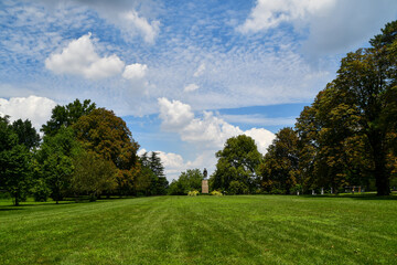 Landscape of great lawn with colonial statue with trees and clouds