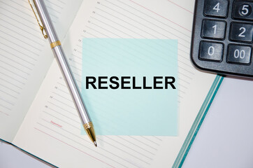 The text reseller is written on a paper blue block near a calculator and notepad. pen next