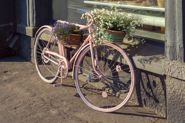 Bicycle in retro style with baskets of flowers on city street