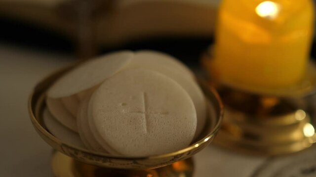 Communion hosts in twilight illuminated by the light of a lit candle