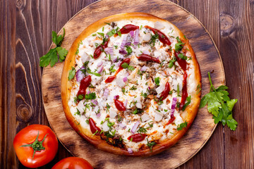 homemade pizza with meat and cheese and vegetables on a wooden table.