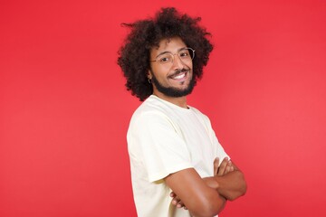 Fototapeta na wymiar Image of cheerful pretty caucasian man standing against gray wall with arms crossed wearing White T-Shirt. Looking and smiling at the camera. Confident successful man.
