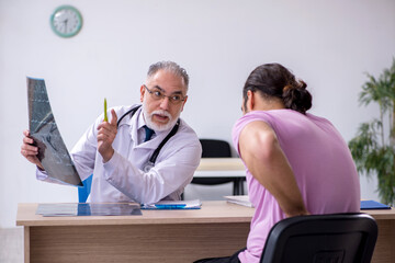 Old doctor radiologist examining young male patient