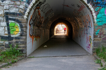 Fototapeta na wymiar Eine Unterführung, Tunnel für Fußgänger und Fahrradfahrer.Die Bruchsteinmauer ist mit Graffiti bemalt.