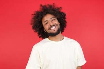 Fototapeta na wymiar Gorgeous smiling male with broad smile, shows white teeth, wears casual t shirt, stands over gray studio wall rejoices having day off. Man standing indoors.