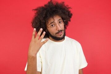 Young man standing against gray wall showing and pointing up with fingers number four while smiling confident and happy. © Jihan