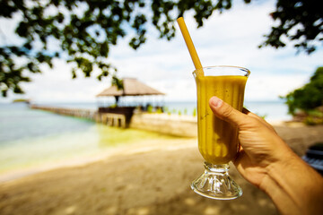 Man drinks mango juice on the beach