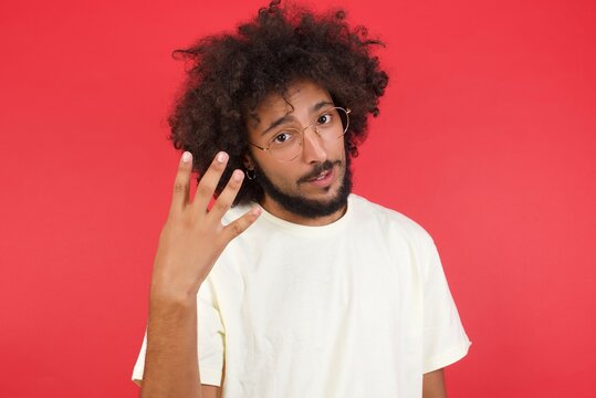 Young man standing against gray wall showing and pointing up with fingers number four while smiling confident and happy.