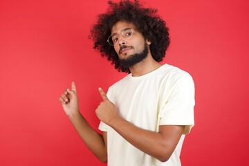 Pretty young man with positive expression, dressed casually, indicates with fore finger at blank...
