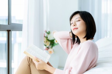Obraz na płótnie Canvas Beautiful Asian woman reading book in bedroom