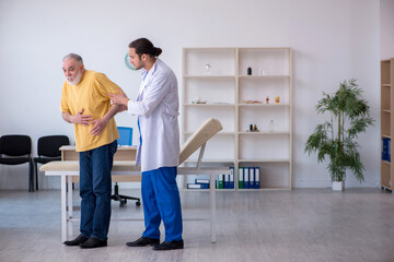 Old injured man visiting young male doctor chiropractor