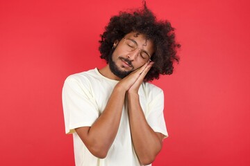 Relax and sleep time. Tired young handsome man with closed eyes leaning on palms as pillow pretending sleeping being exhausted seeing dreams standing against gray background. Sleeping gesture.