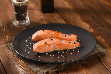 Fried salmon fillet on the black plate.