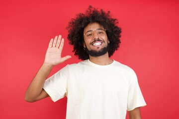 Young handsome man standing over yellow isolated background Waiving saying hello or goodbye happy and smiling, friendly welcome gesture