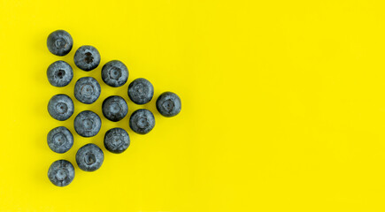 Fresh organic blueberries on yellow background with copy space. View from above, flatlay