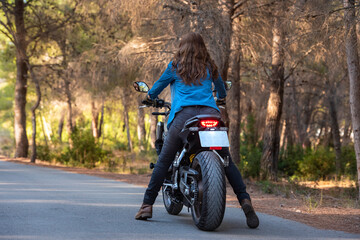 Obraz premium A cheerful young woman with loose, brown hair on a big bike.