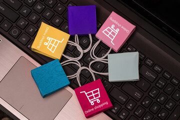 Colorful paper shopping bags put in circle around on notebook keyboard. business concept of online shopping. e-commerce is a transaction of buying or selling products or services online internet.
