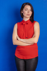 Fototapeta na wymiar Emotional actress young woman in a red blouse posing on a blue background