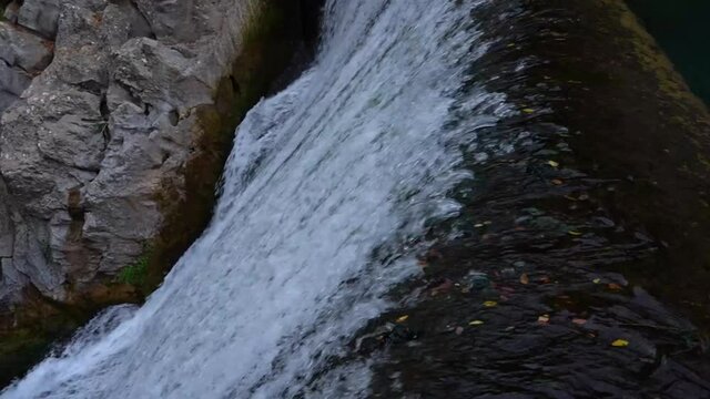 Pan right of a small waterfall flowing with fierce in nature