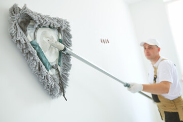 Painter works with triangle drywall cleaning tool. Surface preparation for painting