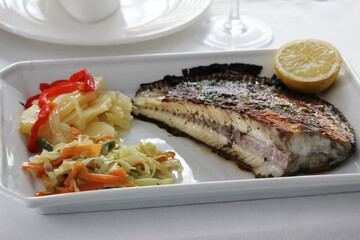Grilled turbot with vegetable garnish and a lemon slice	