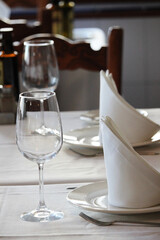 Table set in a restaurant with silverware, wine glasses and napkins
