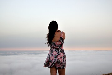 Mujer de espaldas mirando hacia mar de nubes