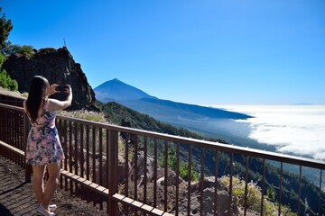 Mujer haciendo una fotografía del Pico del Teide con un mar de nubes de fondo