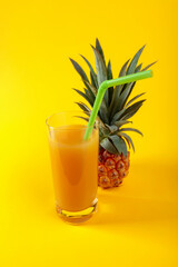 Ripe pineapple and juice on a yellow background.