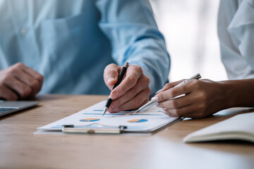 Business people pointing their hands at the data graph to analyze and plan their financial and investment strategy at meeting.