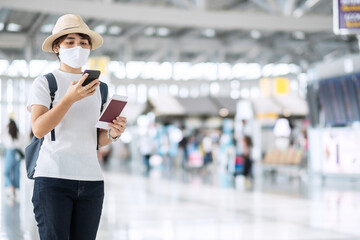 Young adult female with face mask holding passport and smartphone in airport, protection Coronavirus disease infection, Asian woman traveler check flight. New Normal and travel under COVID-19 concept