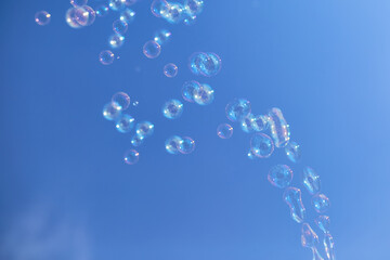 Many soap bubbles against a blue sky