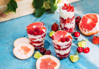 Desserts on blue table with strawberry, raspberry, ice cream and grapefruit