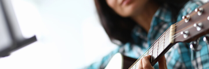 Young woman picks up guitar chords at home couch. Quality distance education during quarantine. Talent for teaching. Learning to play instrument during self-isolation. Instrumental accompaniment