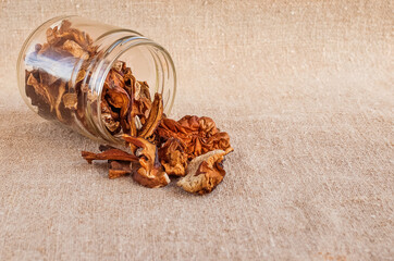 Dried mushrooms in a glass jar scattered on burlap. Organic, eco-friendly food