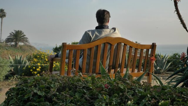 Men sits down on the bench at Laguna Beach low angle